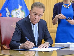 FILE - Connecticut Gov. Ned Lamont signs into law the legalization of recreational-use marijuana on June 22, 2021 in Hartford, Conn. Most eligible Connecticut residents with certain cannabis possession convictions -- roughly 44,000 cases -- should have their records automatically erased within 60 days, or about a month longer than expected under a state law taking effect Jan. 1, Lamont said Wednesday, Dec. 7, 2022.