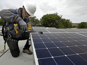 FILE - Gen Nashimoto, of Luminalt, installs solar panels in Hayward, Calif., on April 29, 2020. California air regulators are set to approve an ambitious plan for the state to achieve carbon neutrality by 2045. Doing so will require a rapid transition away from oil and gas and toward renewable energy to power everything from cars to buildings.