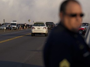 A police officer tries to keep the roadway clear as people come to view the Mauna Loa volcano as it erupts Wednesday, Nov. 30, 2022, near Hilo, Hawaii.