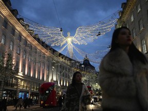 FILE - People walk on Regent Street, in London, on Nov. 17, 2022. Britain's economy shrank in the three months through October, confirming the toll that rampant inflation and rising interest rates are having on business and industry.