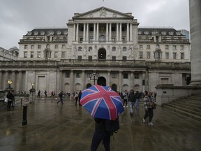 FILE - A woman with an umbrella stands in front of the Bank of England, at the financial district in London, Thursday, Nov. 3, 2022. Britain's central bank is expected to deliver its ninth straight interest rate hike Thursday, Dec. 15 though it will likely be smaller than last month's outsized increase as inflation shows signs of easing.