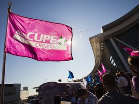 A person holds a flag with the logo of the Canadian Union for Public Employees (CUPE), during a protest about labour disputes at the Toronto Pearson International Airport in 2011.