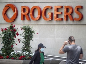 Pedestrians walks past the Rogers Communications Inc. moniker in Toronto.
