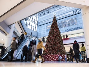 People pass by a large Christmas tree while shopping at a mall in Ottawa on Christmas Eve in 2020.
