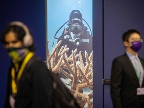 People walk past a poster with a scuba diver during the United Nations Conference of the Parties (COP15) on biodiversity in Montreal.