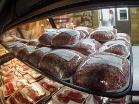 FILE - In this photo made on Thursday, June 16, 2022, fresh meat is seen through the display coolers as a woman enters the retail section at the Wight's Meat Packing facility in Fombell, Pa. On Friday the Labor Department releases the Producer Price Index for November.