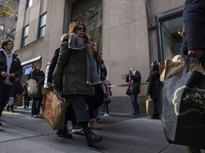 Shoppers carry bags down Fifth Avenue on Friday, Nov. 25, 2022, in New York. The Commerce Department releases retail sales data for November on Friday, Dec. 15.