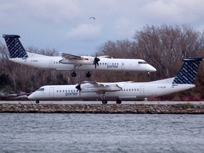 A Porter Airlines plane lands next to a taxiing plane in Toronto.