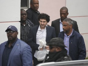 FTX founder Sam Bankman-Fried, center, is escorted from the Magistrate Court in Nassau, Bahamas, Wednesday, Dec. 21, 2022, after agreeing to be extradited to the U.S.