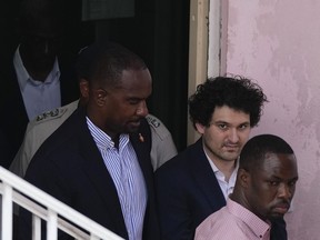 FTX founder Sam Bankman-Fried, second right, is escorted out of Magistrate Court toward a Corrections van, following a hearing in Nassau, Bahamas, Monday, Dec. 19, 2022.