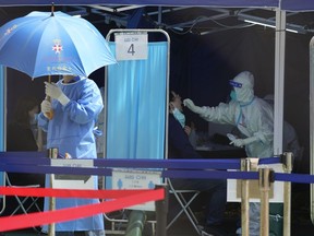 FILE - Medical workers help residents get tested for the coronavirus at a temporary testing center in Hong Kong, Monday, March 14, 2022. Hong Kong will scrap some of its COVID-19 restrictions, including PCR tests for inbound travelers and vaccination requirements to enter certain venues, the city's leader said Wednesday, Dec. 28, 2022.