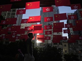 FILE - A man walks past Chinese and Hong Kong flags to celebrate the 25th anniversary of Hong Kong handover to China, in Hong Kong, on June 24, 2022. World Trade Organization arbitrators concluded Wednesday, Dec. 21, 2022, that the United States was out of line in requiring that products from Hong Kong be labeled as "Made in China," a move that was part of Washington's response to a crackdown on pro-democracy protests there in 2019-2020.