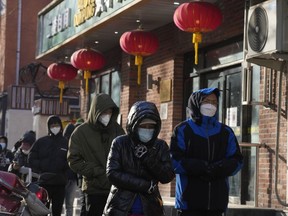 Residents wearing masks line up during a cold day outside a pharmacy to purchase medicine in preparation for a possible wave of COVID-19 outbreaks in Beijing, Tuesday, Dec. 13, 2022. Some Chinese universities say they will allow students to finish the semester from home in hopes of reducing the potential of a bigger COVID-19 outbreak during the January Lunar New Year travel rush.