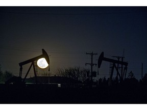 The silhouette of oil pump jacks are seen as the moon rises in Texas, U.S. Photographer: Bloomberg Creative Photos/Bloomberg