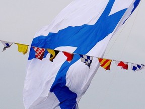 SAINT PETERSBURG, RUSSIA - JULY 26: Andreevsky Flag (the flag of Russian Navy) is seen above mariners standing on a military ship on July 26, 2015 in St Petersburg, Russia. Introduced in 1939 by the Soviet government as a national holiday, Navy Day in Russia is celebrated annually on the last Sunday of July.