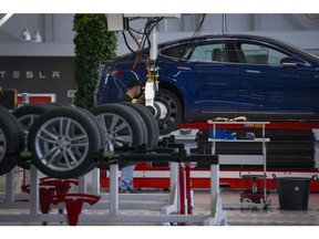 An employee fits a rear wheel to a Tesla Model S automobile on the final assembly line at the Tesla Motors Inc. factory in Tilburg, Netherlands, on Thursday, Oct. 8, 2015.  Photographer: Jasper Juinen/Bloomberg