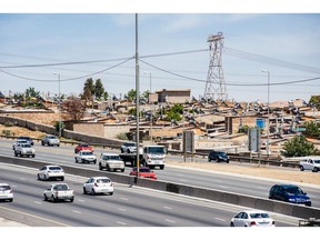 A pylon tower carries electrical power lines over residential shacks, some equipped with solar power geysers on their roofs, near a highway in the Alexandra township outside Johannesburg, South Africa, on Thursday, Oct. 6, 2016. Eskom Holdings SOC Ltd. is building new electricity stations to end the power cuts that were imposed for about 100 days last year, curbing growth in Africa's most-industrialized nation.