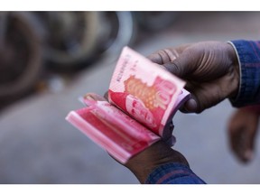 A roadside money changer counts Pakistani one hundred rupee banknotes at a currency exchange market in Karachi, Pakistan, on Thursday, Dec. 14, 2017. Pakistan's rupee weakened to a record low after the central bank continued to ease its grip on the currency amid mounting economic pressure and speculation that the country may need International Monetary Fund support. Photographer: Asim Hafeez/Bloomberg