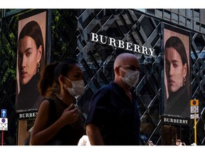 Pedestrians wearing protective masks walk past a Burberry Group Plc store on Canton Road in the Tsim Sha Tsui district of Hong Kong, China, on Sunday, July 26, 2020. Having briefly shown signs of recovery in recent months from its deepest recession on record, the Asian financial hub is bracing for its stiffest test yet as a resurgent virus combines with an increasingly uncertain political and financial outlook.