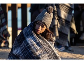 A Colombian immigrant bundles up against the cold after spending the night camped alongside the U.S.-Mexico border fence on Dec. 22, 2022 in El Paso, Texas.