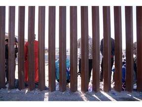 Migrants wait at the US and Mexico border wall in El Paso, Texas, on Dec. 22, 2022. Photographer: Eric Thayer/Bloomberg