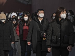 FILE - People wearing face masks walk along a street in Beijing, Friday, Jan. 6, 2023. China has suspended or closed the social media accounts of more than 1,000 critics of the government's policies on the COVID-19 outbreak, as the country moves to further open up.