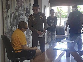 Peter Coker Jr., left, is issued search warrants from police at his villa on the southern resort island of Phuket, Thailand, Jan. 11, 2023. Coker Jr., who used to work in Hong Kong and who is wanted in connection with an alleged stock manipulation scheme that led a small New Jersey delicatessen to be listed as a public company worth $100 million, has agreed to his voluntary extradition to the United States after being arrested last week on the resort island of Phuket, a Thai legal official said Friday, Jan. 20, 2023. (Crime Suppression Division, Royal Thai Police. via AP)