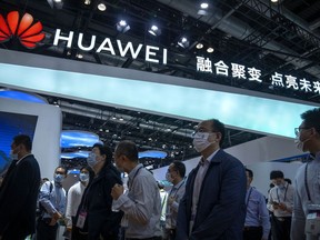 FILE - Visitors walk past a booth for Chinese technology firm Huawei at the PT Expo in Beijing on Sept. 28, 2021. China's government accused Washington on Tuesday, Jan. 31, 2023, of pursuing "technology hegemony" following news reports the United States might step up pressure on tech giant Huawei by blocking all access to American suppliers.