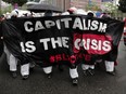 Climate activists carrying a banner reading "capitalism is the crisis" protest outside the European Central Bank in Frankfurt, Germany in 2020.