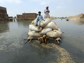 Flood victims from monsoon rain use a makeshift barge to carry hay for cattle, in Jaffarabad, a district of Pakistan's southwestern Baluchistan province, on Sept. 5, 2022.