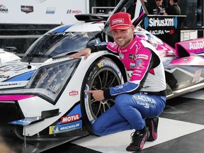 Tom Blomqvist, of New Zealand, kneels next to his Acura ARX-06 GDP after winning the pole position for the Rolex 24 hour auto race at Daytona International Speedway, Sunday, Jan. 22, 2023, in Daytona Beach, Fla.