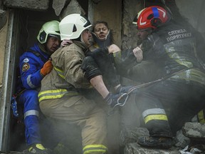 In this photo released by State Emergency Service of Ukraine on Monday, Jan. 16, 2022, Ukrainian State Emergency Service firefighters carry a wounded woman out of the rubble from a building after a Russian rocket attack on Saturday in Dnipro, Ukraine, Sunday, Jan. 15, 2023.