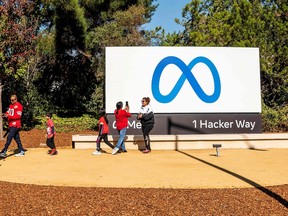 People take photos in front of the Meta Platforms' logo at the company's headquarters in Menlo Park, Calif.