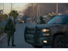 Mexicans soldiers stand guard near burning vehicles on a street during an operation to arrest the son of Joaquin "El Chapo" Guzman, Ovidio Guzman, in Culiacan, Sinaloa state, Mexico, on January 5, 2023. Photographer: Juan Carlos Cruz/AFP/Getty Images
