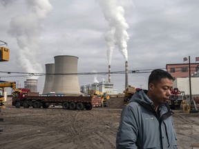 A person walks past a coal fired power plant in Jiayuguan, Gansu province, China.