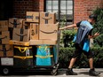 An Amazon.com Inc. delivery worker pulls a delivery cart full of packages in New York City, U.S.