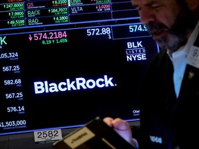 A trader works as a screen displays the trading information for BlackRock Inc. on the floor of the New York Stock Exchange.