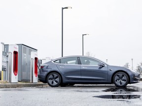 Tesla owners using charging stations in a parking lot.