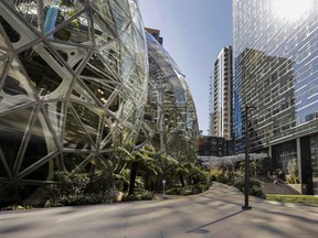 FILE - The light reflects off the glass facade of a building on the Amazon campus outside the company headquarter on March 20, 2020, in Seattle. The company said Wednesday, Jan. 4, 2023, that it will be cutting about 18,000 positions.