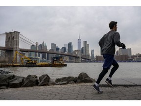 A man jogs in front of the skyline of lower Manhattan and the Brooklyn Bridge on January 25, 2023 in New York City.  Photographer: Angela Weiss/AFP/Getty Images