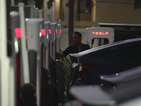 FILE - A driver charges his car at a Tesla Supercharger station, Wednesday, Nov. 16, 2022, in Miami. A tweet from Elon Musk indicating that Tesla might allow some owners who are testing a "Full Self-Driving" system to disable an alert that reminds them to keep their hands on the steering wheel has drawn attention from U.S. safety regulators.