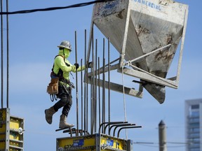 A worker guides a bin into position at a construction site, Tuesday, Jan. 24, 2023, in Miami. The Commerce Department issues its first of three estimates of how the U.S. economy performed in the fourth quarter of 2022. On Thursday, the Commerce Department issues its first of three estimates of how the U.S. economy performed in the fourth quarter of 2022.