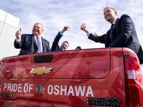 Ontario Premier Doug Ford, left, and Federal Minister of Innovation, Science and Industry François-Philippe Champagne, right,)sit in the back of a pickup truck at a General Motors facility in Oshawa, Ont., on April 4, 2022.