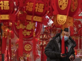 A man wearing a face mask shops for Chinese Lunar New Year decorations at a pavement store in Beijing, Saturday, Jan. 7, 2023. China has suspended or closed the social media accounts of more than 1,000 critics of the government's policies on the COVID-19 outbreak, as the country moves to further open up.