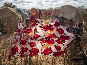 FILE - Children stand near shelters at a camp for displaced people on the outskirts of Dollow, Somalia, Sept. 19, 2022.