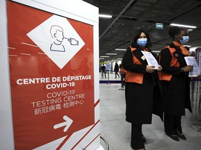 Airport staff wait from passengers coming from China in front of a COVID-19 testing area set at the Roissy Charles de Gaulle airport, north of Paris, Sunday, Jan. 1, 2023. France says it will require negative COVID-19 tests of all passengers arriving from China and is urging French citizens to avoid nonessential travel to China.
