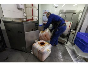 A worker collects vats of hot pot waste oil at a restaurant in Chengdu. Photographer: Qilai Shen/Bloomberg