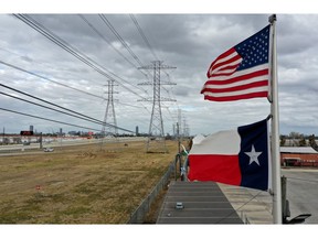 HOUSTON, TEXAS - FEBRUARY 21: The U.S. and Texas flags fly in front of high voltage transmission towers on February 21, 2021 in Houston, Texas. Millions of Texans lost power when winter storm Uri hit the state and knocked out coal, natural gas and nuclear plants that were unprepared for the freezing temperatures brought on by the storm. Wind turbines that provide an estimated 24 percent of energy to the state became inoperable when they froze.
