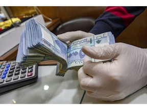 A worker wearing protective gloves counts Lebanese pound banknotes at a currency exchange kiosk on Hamra street in Beirut, Lebanon, on Wednesday, April 14, 2021. Lebanon's annual inflation rate reached a record high and food prices soared by around 400% in December, highlighting the dramatic impact on consumers and businesses of the country's worst financial crisis in decades. Photographer: Francesca Volpi/Bloomberg