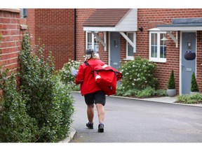 A post woman for Royal Mail Plc carries a bag of post for delivery in Chelmsford, U.K., on Thursday, May 13, 2021. Royal Mail are due to report earnings on Thursday, May 20.